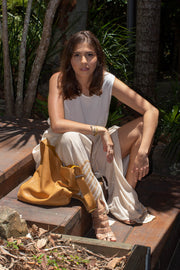 Seated model wears Ripple and Co Leather Cross Shoulder Bag Tan
